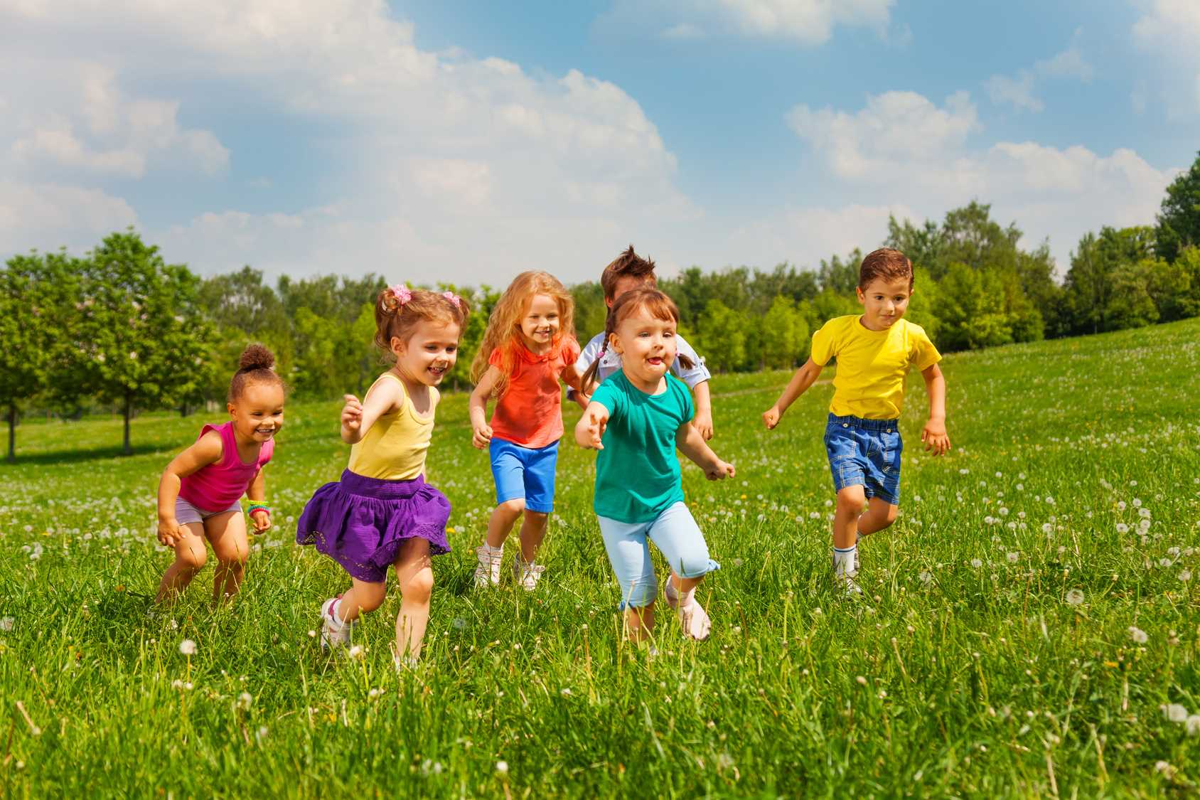 Развлечения на поляне. Счастливые дети бегут. Занятия летом. Дети на свежем воздухе. Дети бегают.